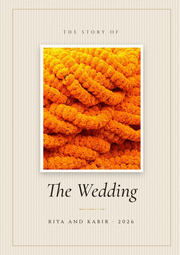 An ivory linen cover with a framed photo of marigold garlands and The Wedding in serif