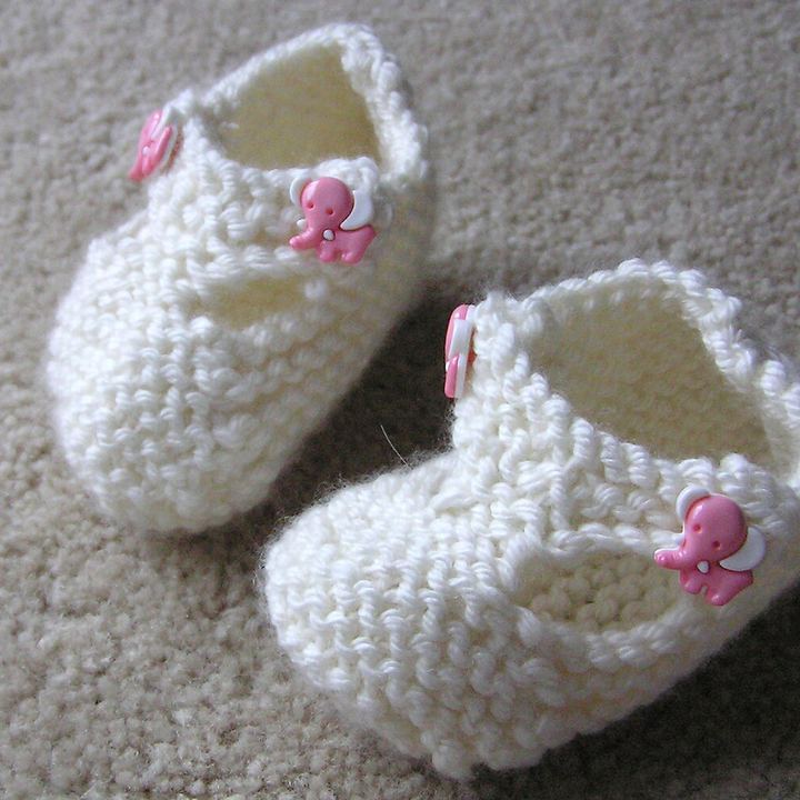 A pair of knitted baby booties on a soft blanket